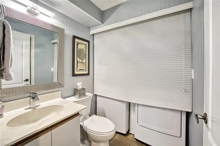 First floor full bath with shower with wood-like style floors and washer/dryer area