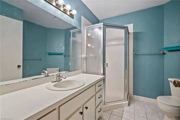 Bathroom featuring walk in shower, tile patterned flooring, vanity, and toilet