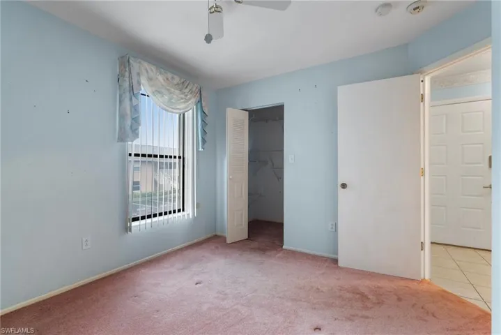 Unfurnished bedroom featuring ceiling fan, a closet, a walk in closet, and light colored carpet