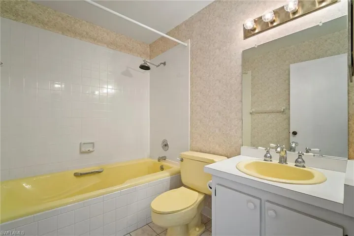 Full bathroom with vanity, tile patterned floors, toilet, and tiled shower / bath