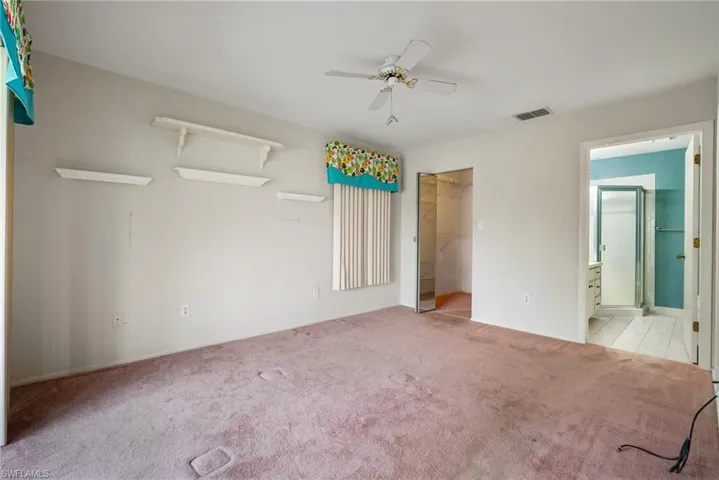 Unfurnished bedroom with light carpet, connected bathroom, ceiling fan, a closet, and a spacious closet