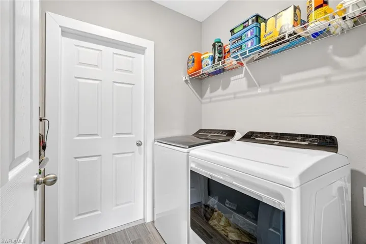 Laundry room with washer and clothes dryer and light wood-style floors