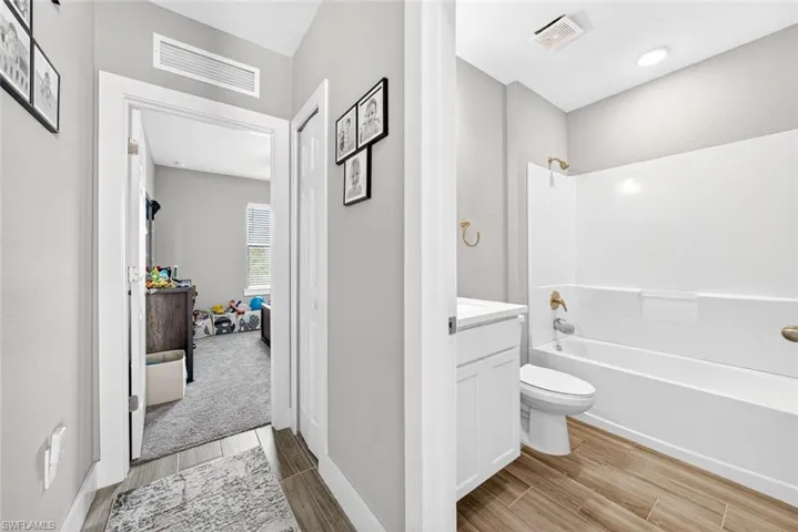 Bathroom with vanity, wood finish floors, and bathtub / shower combination