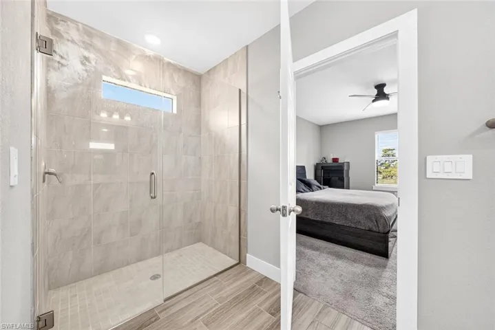Full bath featuring healthy amount of natural light, a stall shower, ensuite bath, and a ceiling fan