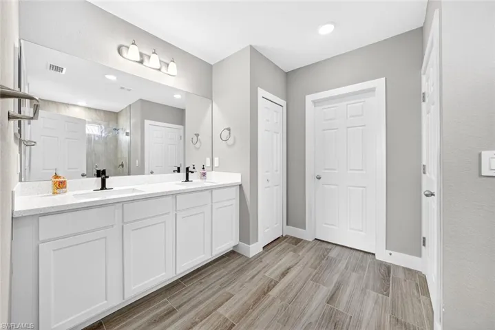 Full bath featuring a shower stall, double vanity, wood tiled floors, recessed lighting, and a closet
