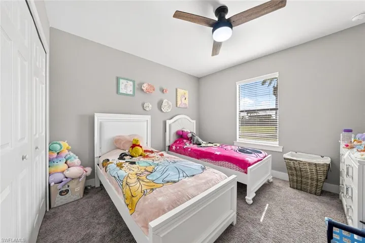Carpeted bedroom with ceiling fan and a closet