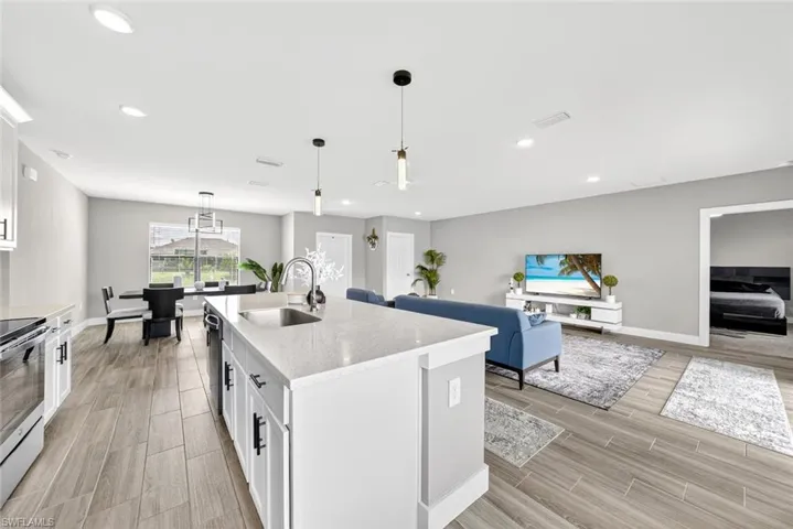 Kitchen with white cabinets, decorative light fixtures, wood finish floors, and recessed lighting