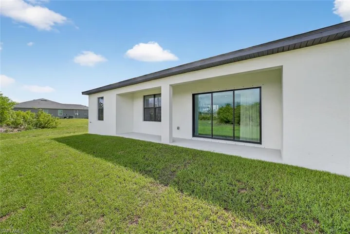 Rear view of property with stucco siding, a yard, and a patio area
