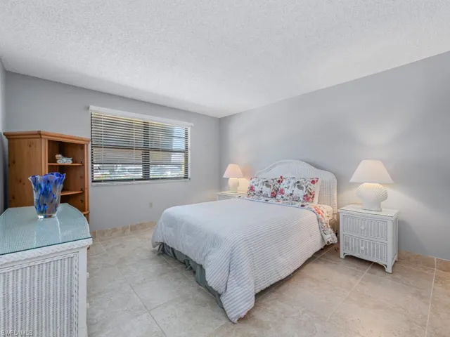Tiled bedroom featuring baseboards and a textured ceiling