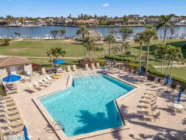 Community pool featuring a patio, a residential view, fence, and a water view