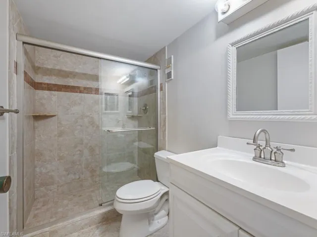 Full bathroom with a shower stall, tile patterned floors, vanity, and toilet