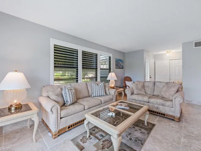 Tiled living room with a textured ceiling, baseboards, and visible vents