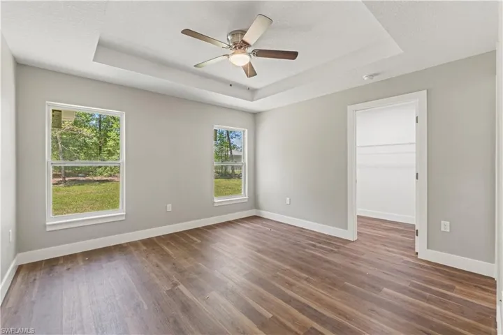 Spare room featuring a tray ceiling, dark wood finished floors, a ceiling fan, and a textured ceiling