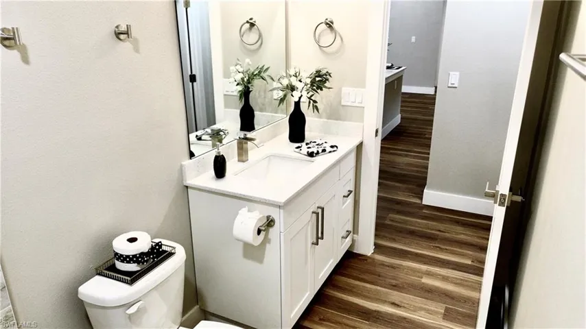 Bathroom with vanity, dark wood-style floors, and a textured wall