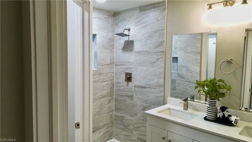 Full bath with double vanity and a tile shower
