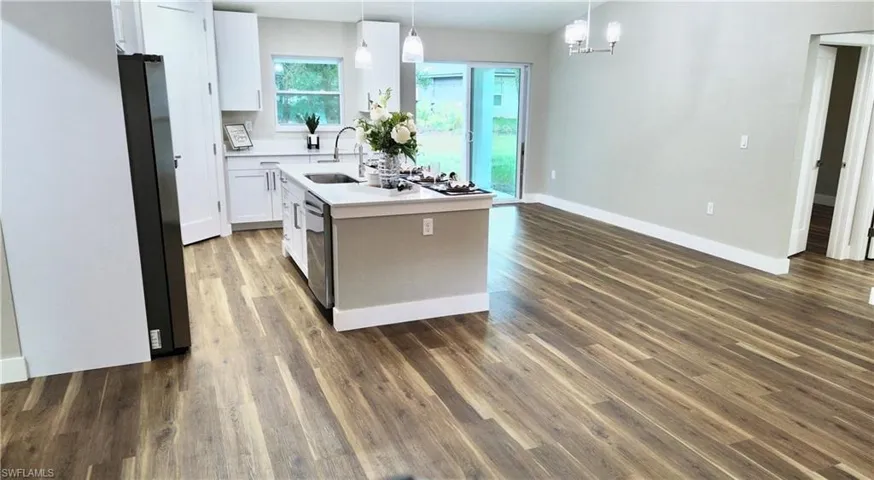 Kitchen with pendant lighting, white cabinetry, stainless steel appliances, and dark wood finished floors