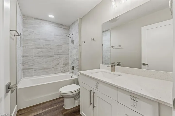 Bathroom featuring vanity, shower / tub combination, and dark wood-style floors