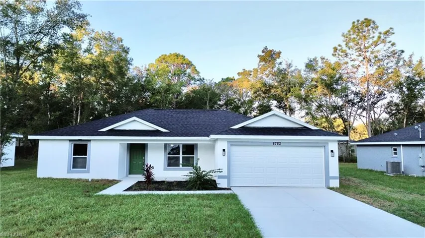 Ranch-style house with a front lawn, stucco siding, driveway, roof with shingles, and a garage
