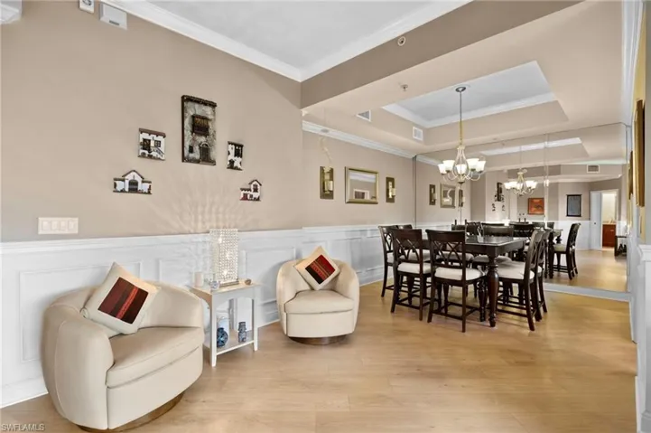 Dining room featuring a notable chandelier, a tray ceiling, crown molding, and light wood-type flooring