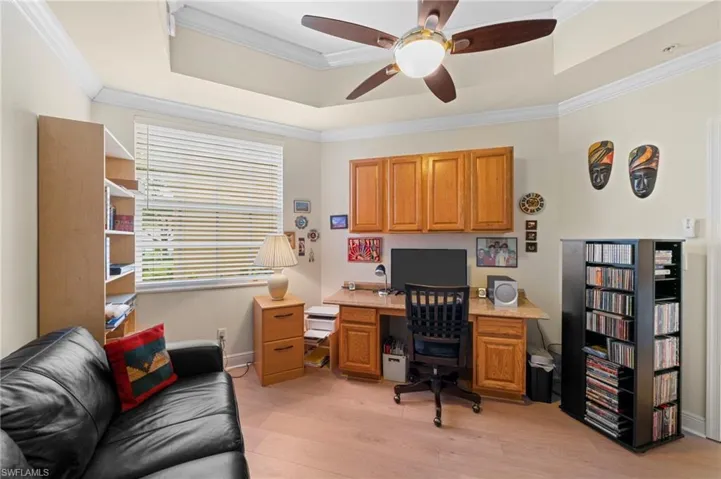 Office area with ornamental molding, a tray ceiling, and light wood-type flooring