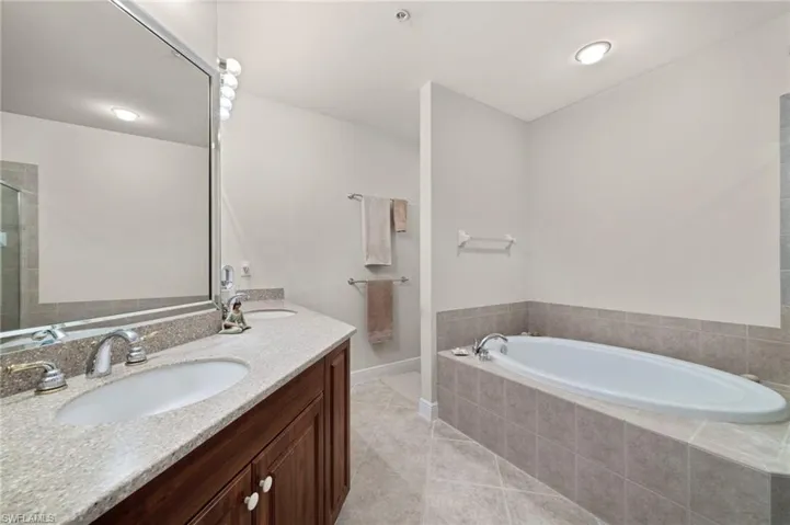 Bathroom with a relaxing tiled bath, tile flooring, and vanity