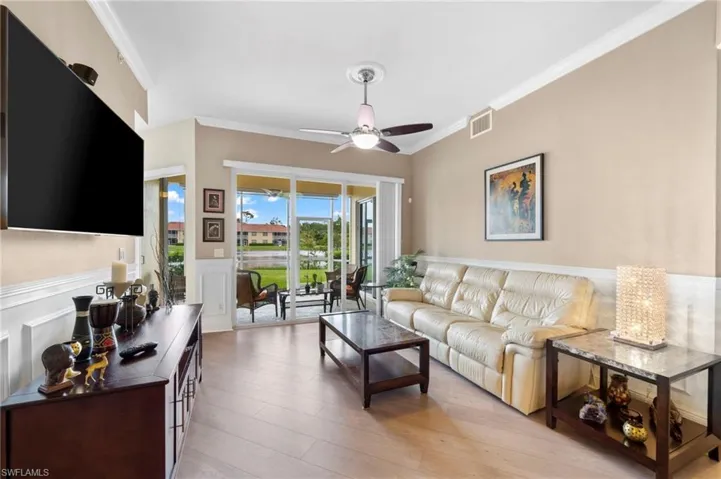 Living room featuring ornamental molding, light wood-type flooring, and ceiling fan