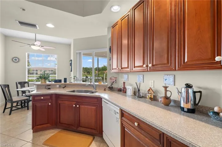 Kitchen featuring sink, ceiling fan, light tile flooring, and white dishwasher