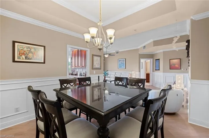 Dining area with a tray ceiling, crown molding, a chandelier, and light hardwood / wood-style flooring