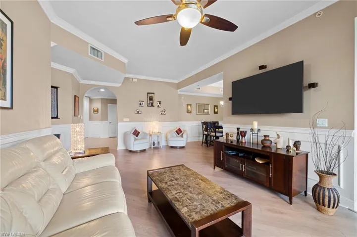 Living room with ceiling fan, ornamental molding, and wood-type flooring