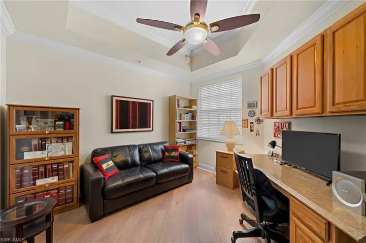 Office with ceiling fan, a tray ceiling, crown molding, and light wood-type flooring