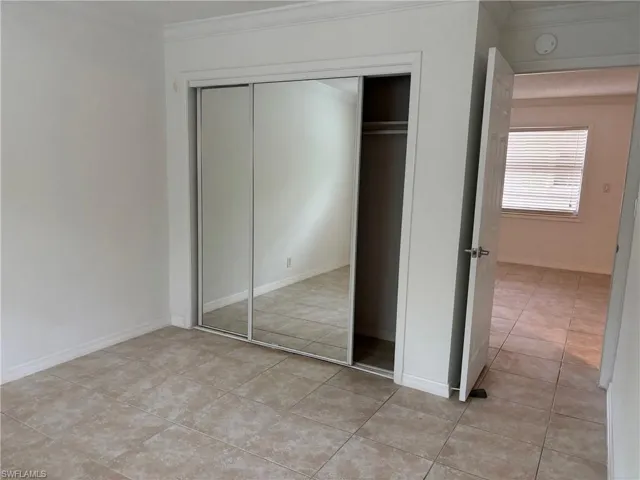 Unfurnished bedroom featuring a closet, light tile patterned floors, and ornamental molding
