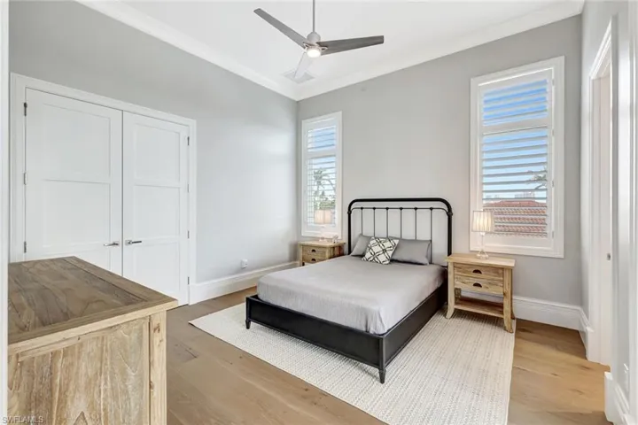 Bedroom featuring ornamental molding, light wood-type flooring, baseboards, a ceiling fan, and a closet