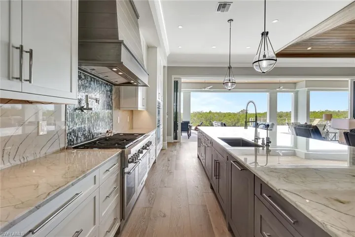 Kitchen with custom range hood, range with two ovens, light wood-style floors, white cabinetry, and recessed lighting