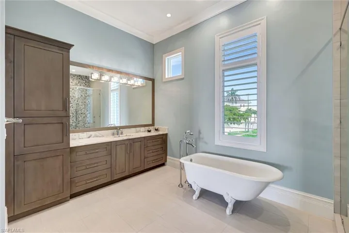 Master Bathroom with a shower stall, a freestanding tub, vanity, baseboards, and crown molding
