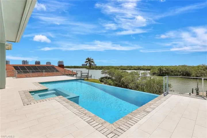 View of swimming pool featuring a pool with connected hot tub, a patio area, and a water view