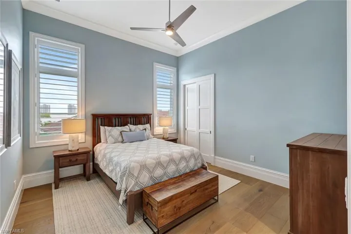 Guest 1 Bedroom featuring light wood-style flooring, baseboards, crown molding, and a ceiling fan