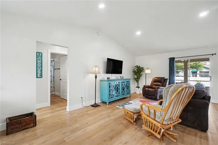 Vaulted ceiling living area featuring wood-finish flooring, recessed lighting, and a sliding glass door