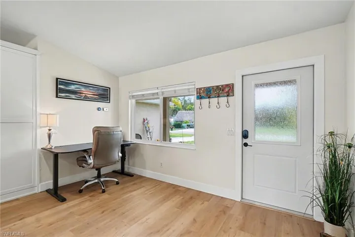 Wood-finish flooring throughout, white trim, and a white paneled door with a frosted glass insert