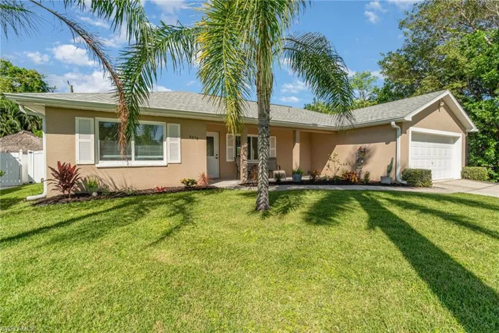 Stucco exterior with white shutters, an attached garage, and landscaping with mature trees