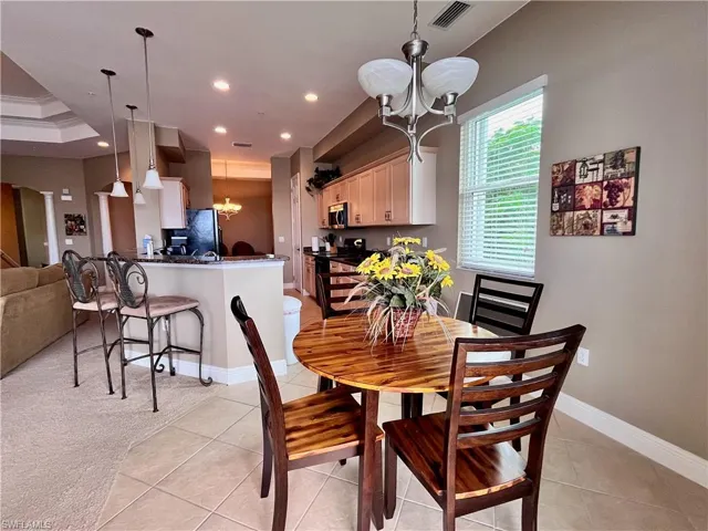 Eat in Kitchen dining featuring a chandelier, light tile patterned floors, recessed lighting, and light carpet with views of the water