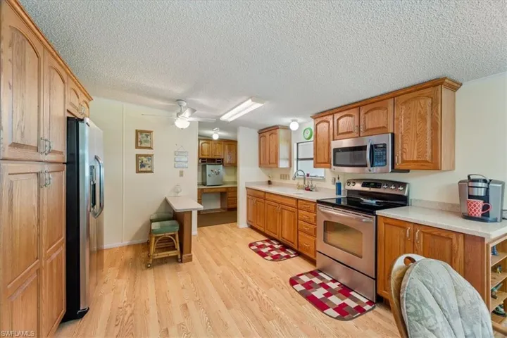 Kitchen with sink, light hardwood / wood-style flooring, a textured ceiling, appliances with stainless steel finishes, and ceiling fan