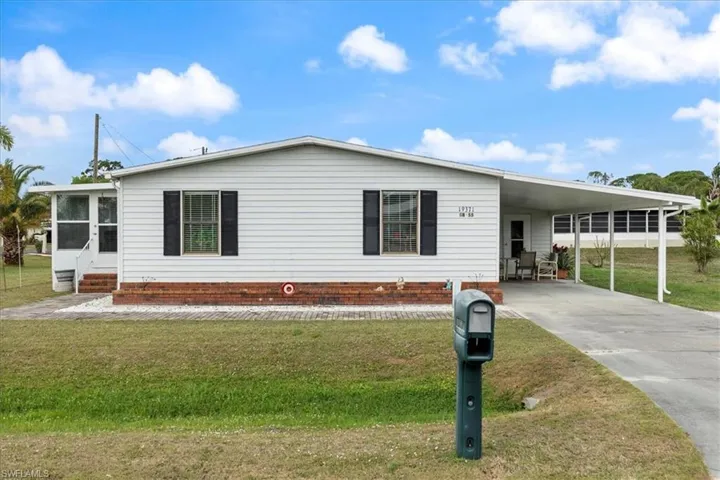 View of front facade with a carport and a front lawn