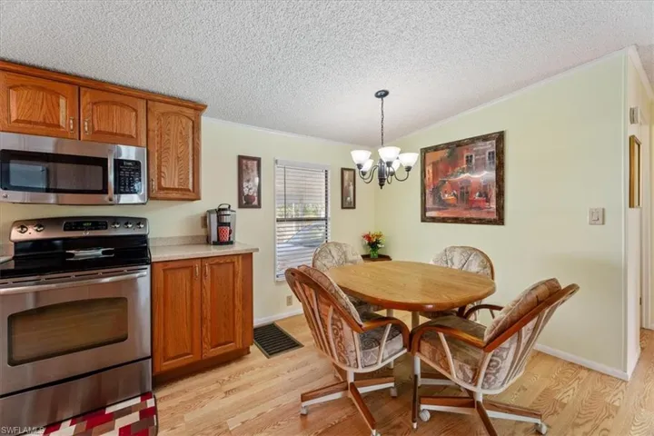 Kitchen featuring pendant lighting, ornamental molding, stainless steel appliances, and light wood-type flooring