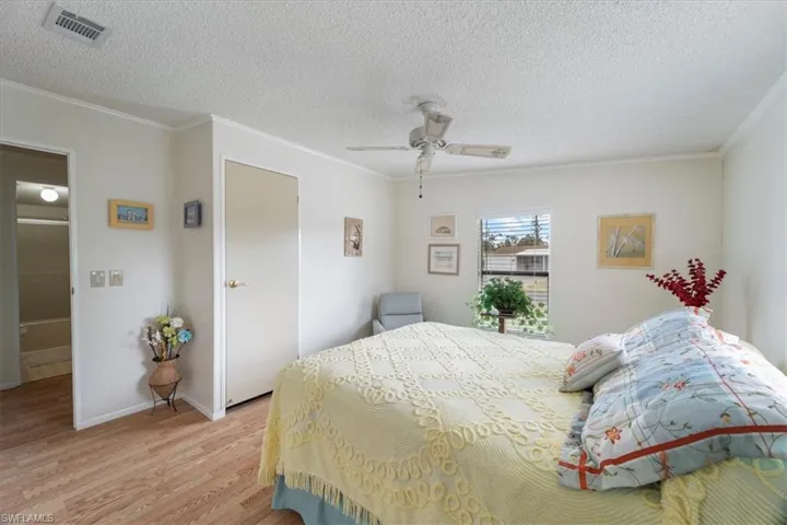 Bedroom featuring ceiling fan, ornamental molding, a textured ceiling, and light wood-type flooring