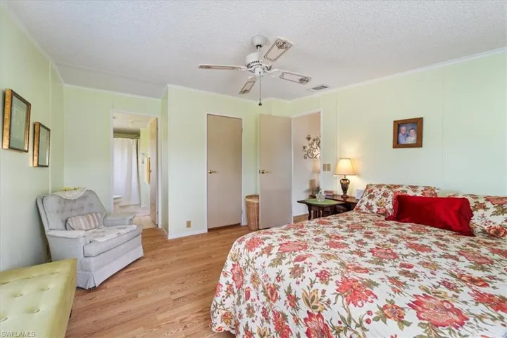Bedroom featuring ceiling fan, ornamental molding, a textured ceiling, and light wood-type flooring