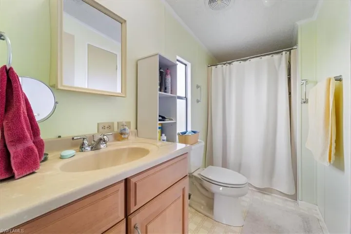 Bathroom with vanity, ornamental molding, walk in shower, toilet, and a textured ceiling