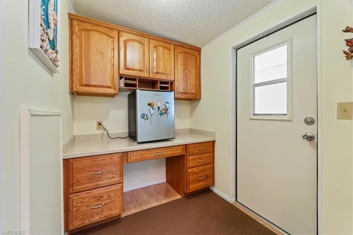 Unfurnished office featuring crown molding, built in desk, and a textured ceiling