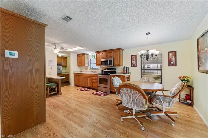 Dining room featuring sink, ceiling fan with notable chandelier, light hardwood / wood-style floors, and a textured ceiling