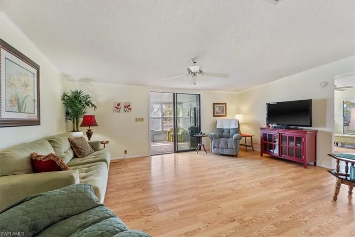 Living room featuring crown molding, ceiling fan, light hardwood / wood-style flooring, and a textured ceiling