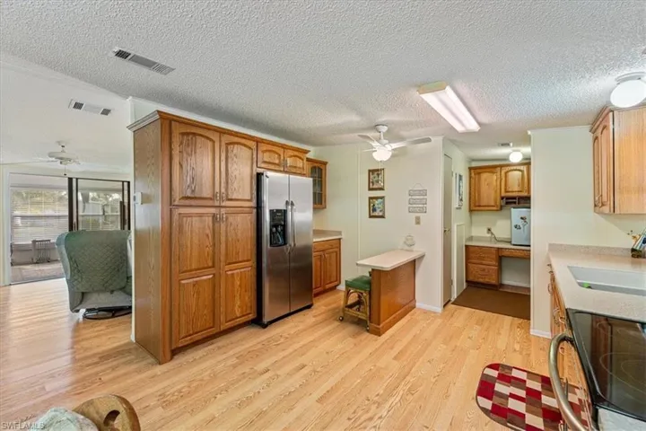 Kitchen with sink, built in desk, light wood-type flooring, ceiling fan, and stainless steel appliances